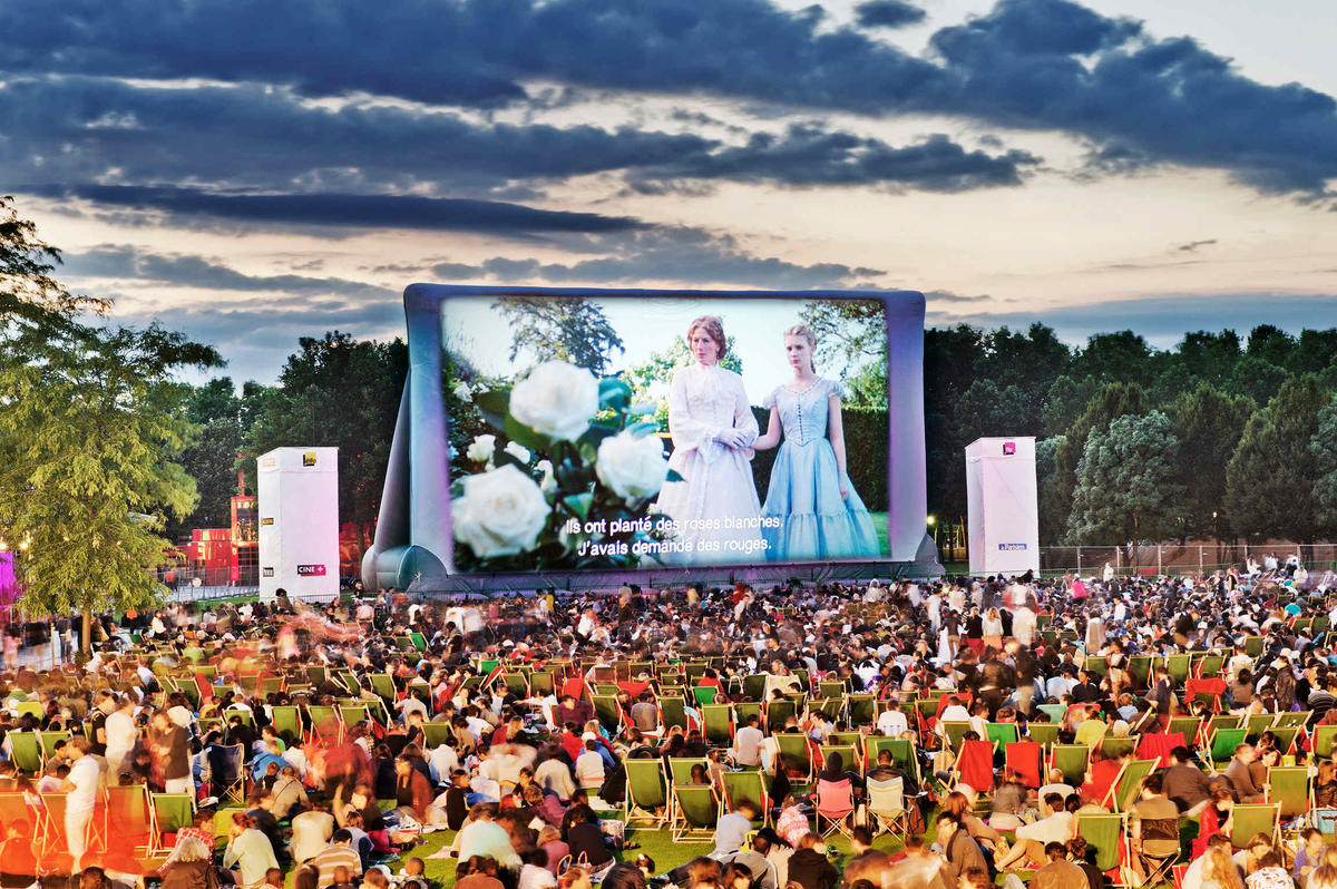 Open air cinema under starlit sky with comfortable seating and large outdoor screen